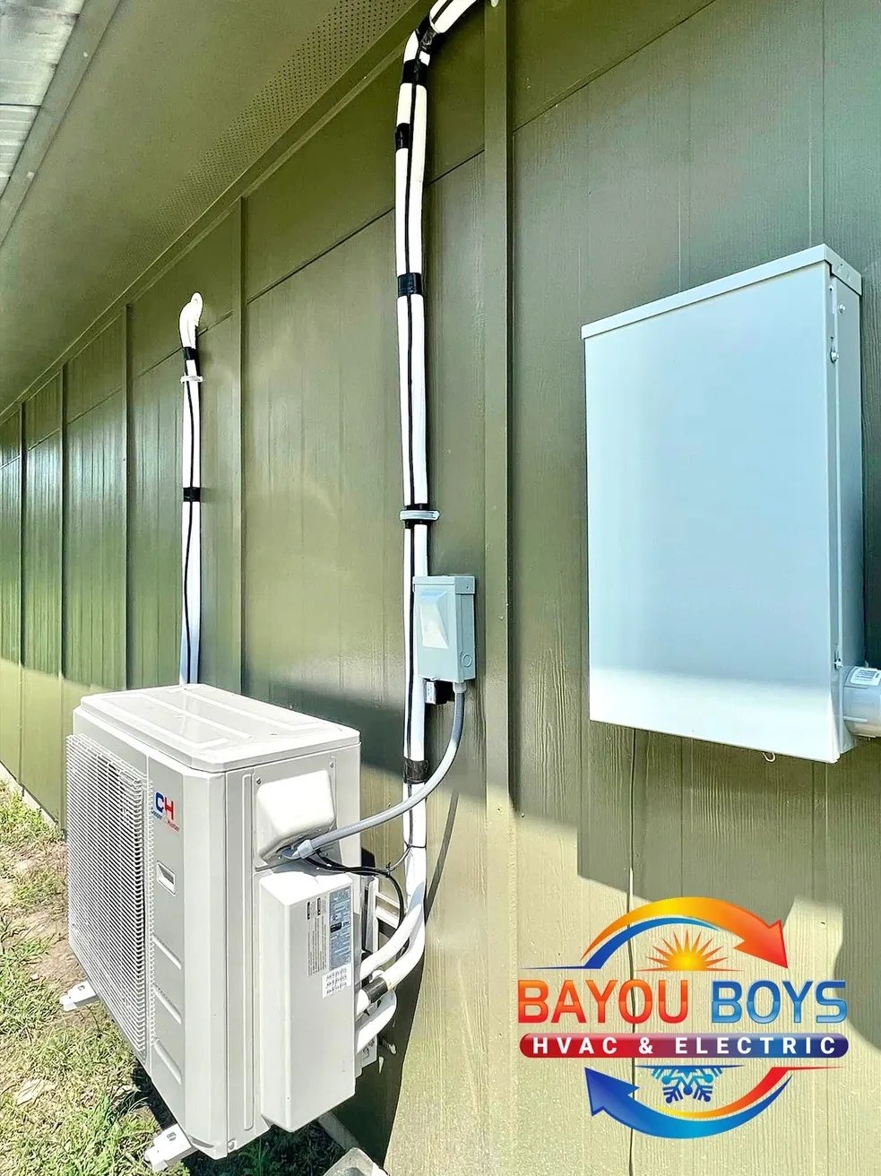 Outdoor HVAC unit mounted on green wall with electrical connections