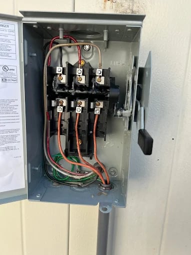Open electrical panel with copper and green wires and circuit breakers