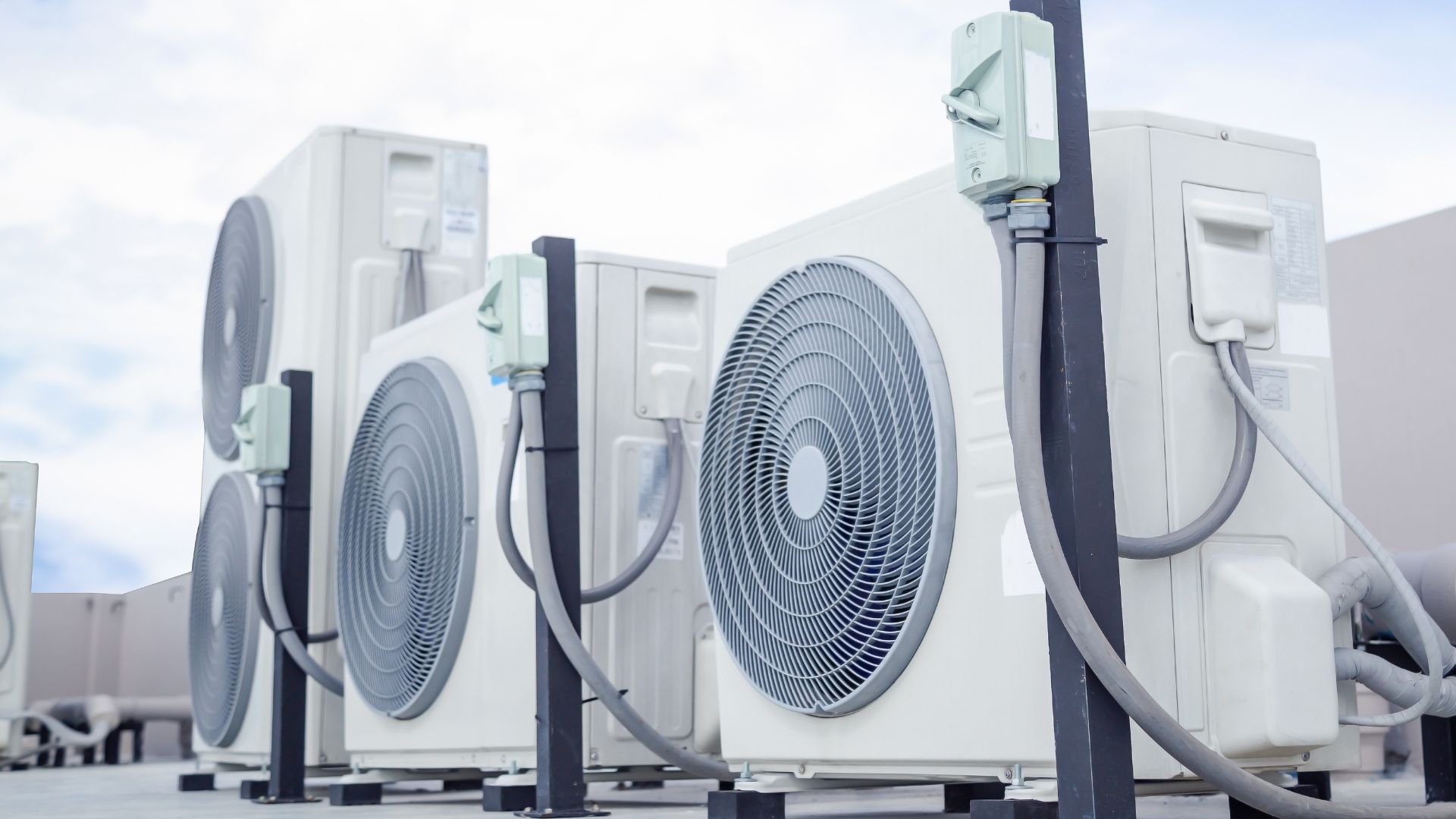 Multiple white air conditioning units with large circular fans mounted outdoors