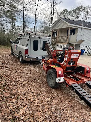 Red tractor and service van parked near house on leaf-covered ground