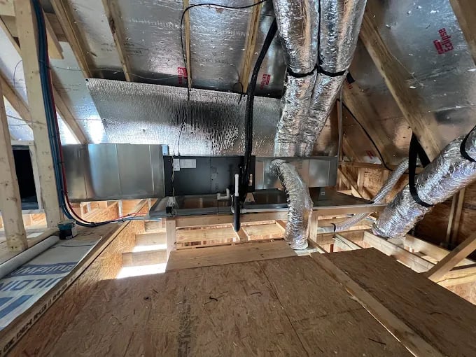 HVAC ductwork and insulation installed in unfinished wooden attic or crawl space
