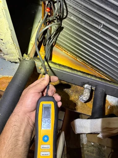 Technician using yellow gas leak detector near industrial equipment